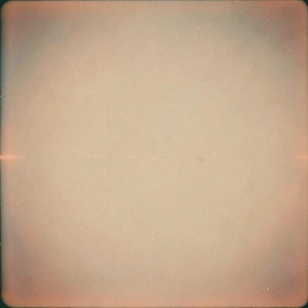 Wide soft-focus film photograph of a rustic wooden table dusted with flour and pastel icing tools, warm cream and sage tones, cozy grainy mood